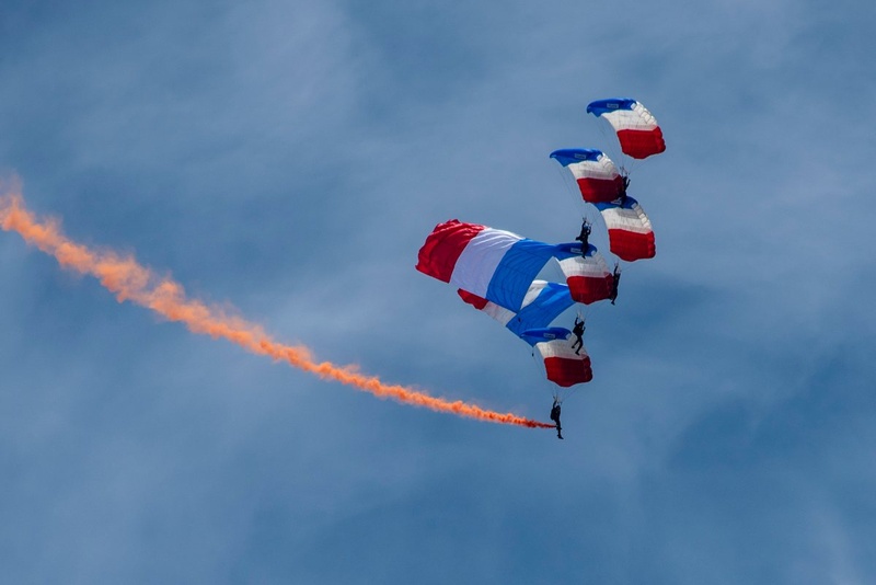 Parachutists under blue, white and red canopies above Le Bourget.
